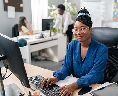 Professional African American Woman at Computer smiling at Camera